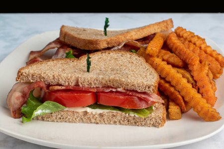 Téléchargez les photos : Laitue au bacon et tomate sur pain de blé servi avec des frites - en image libre de droit