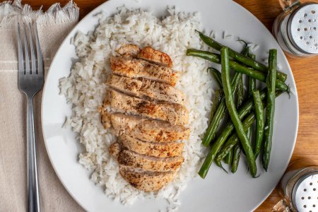sliced season chicken breast  on white rice served with sauteed green beans