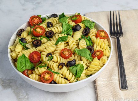 Téléchargez les photos : Pâtes rotini sevred avec tomates, épinards et olives noires - en image libre de droit