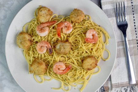 Foto de Vieiras y camarones servidos con espaguetis con queso y perejil. - Imagen libre de derechos