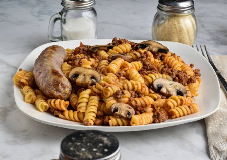 Téléchargez les photos : Pâtes rotini avec sauce pour pâtes à la viande et champignons servis avec des saucisses italiennes - en image libre de droit