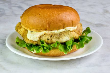 cod fillet sandwich  with lettuce and tarter sauce  served on a brioche bun