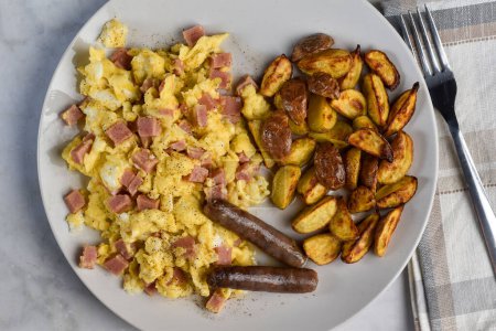 scramble eggs mixed with spam and  served with sausages and a side of home fries