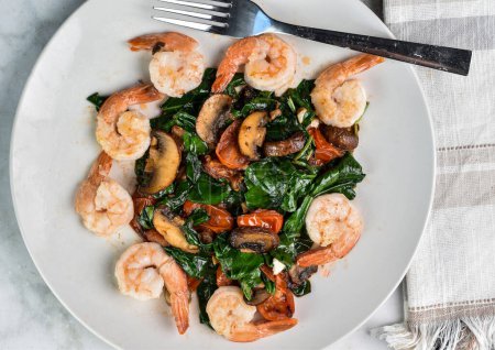 dish of sauteed spinach,  tomatoes and mushrooms served with  shrimp
