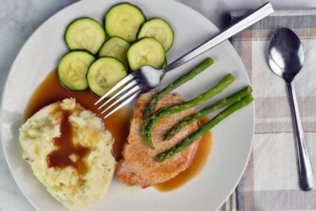 pork chop top with asparagus  and served  with zucchini and mash potatoes