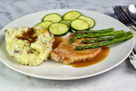 pork chop top with asparagus  and served  with zucchini and mash potatoes