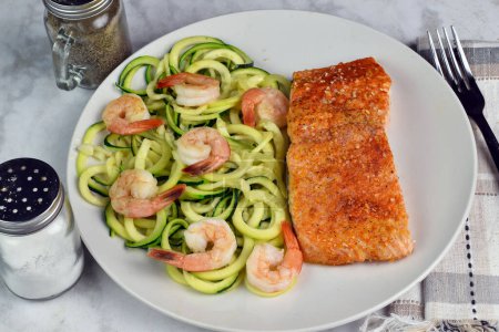 baked season salmon served with zucchini noodle  and shrimp.,