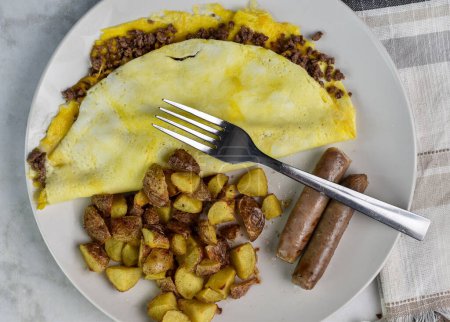 cheese burger  omelet served with breakfast sausage and homefries