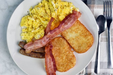 scramble egg top with parsley served with bacon, sausage and hash browns,