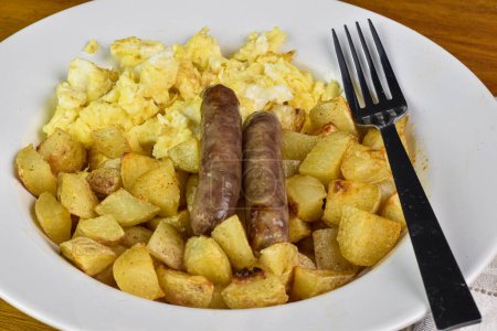 breakfast plate  of scramble eggs served with home fries and sausages, 