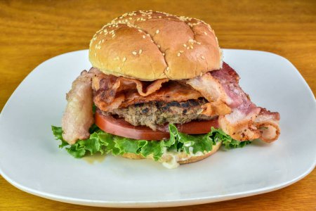 hamburger with bacon lettuce and tomato on sesame bun