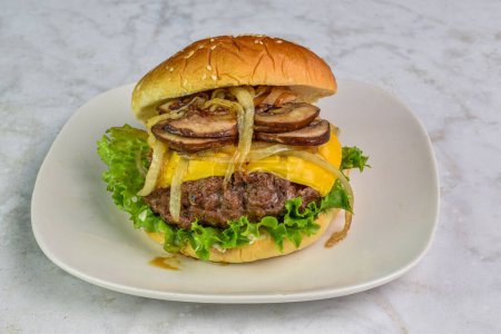 onions and mushrooms  on a juicy cheese burger resting on sesame bun
