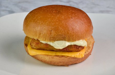 fish fillet  with melted cheese and  tarter sauce on a brioche bun 