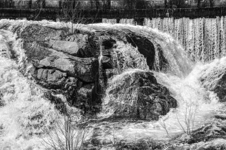  black and whiye photo of water  crashing over crashing over rocks in the quabbin spillway at the quabbin reservoir in ware massachusetts.
