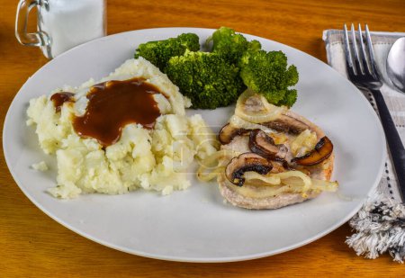 baked pork chop top with oniond and mushrooms served  with broccoli and mashed potatoes