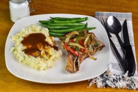 pork chop  top with peppers and onions  with mash potatoes  and green beans, 
