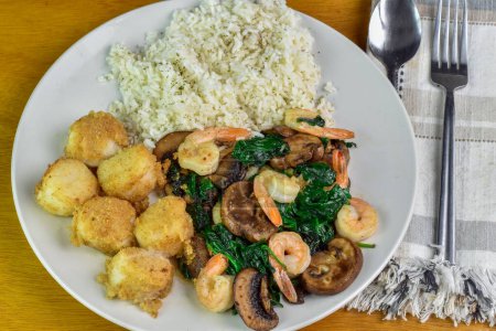 scallops with sauteed shrimp spinach and mushrooms served vwith rice