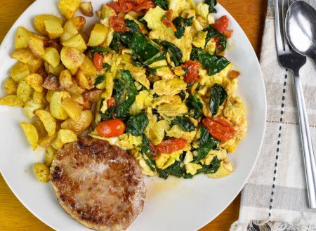 scramble eggs with sauteed spinach and tomatoes  served with home fries and sausage patty, 