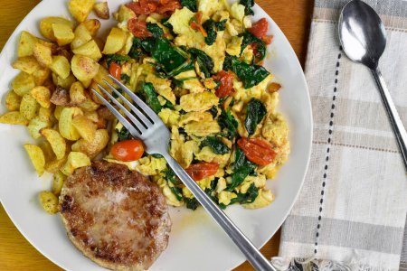 scramble eggs with sauteed spinach and tomatoes  served with home fries and sausage patty,
