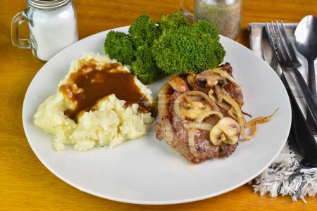 boneless steak top with onions and mushrooms served with mash potatoes