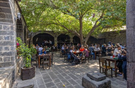 Téléchargez les photos : Diyarbakir, Turquie, 5 octobre 2023 : Des personnes non identifiées s'assoient dans la cour de Suluklu Khan, une auberge médiévale utilisée pour les cafés et les petits magasins aujourd'hui à Diyarbakir - en image libre de droit