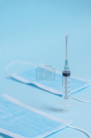 Syringe with cap isolated on light blue background, closeup. Biosafety elements.