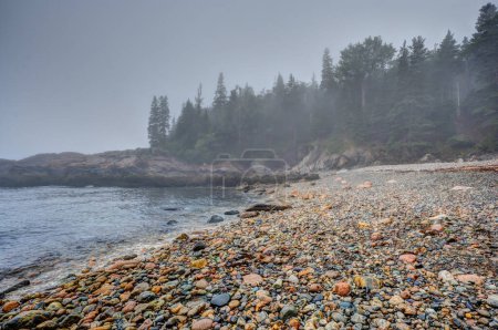 Multi-colored round rocks on Little Hunters Beach in Acadia National Park, Maine. Tide coming in as waves crash. . High quality photo