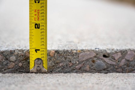 Photo for Frost heave crack in residential concrete sidewalk with tape measure . High quality photo - Royalty Free Image