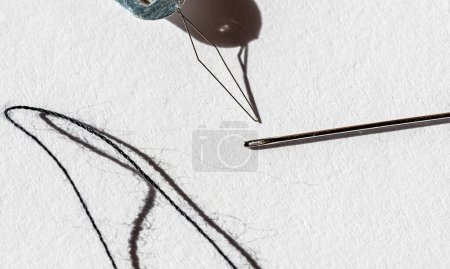 Téléchargez les photos : Outil à coudre l'aiguille en cours d'utilisation et une seule corde noire. . Photo de haute qualité - en image libre de droit