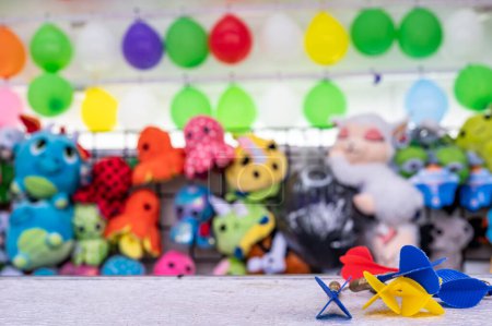 Photo for Selective focus on darts sitting on a ledge with a wall of balloon targets and prizes that a player can win at a fair. High quality photo - Royalty Free Image