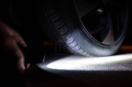 Téléchargez les photos : Fond sombre avec faisceau de ligh visant un pneu d'automobile - en image libre de droit