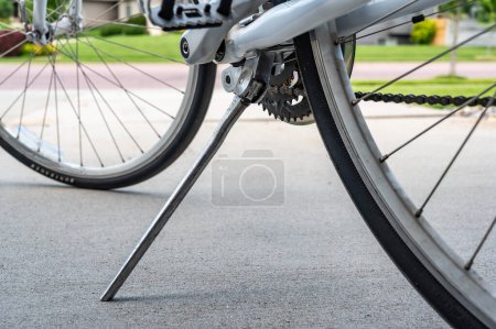 Photo for Metal kick stand extended to support a parked bike on a concrete surface. - Royalty Free Image
