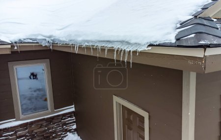 Erhöhter Blick auf einen Eisdamm und Schnee auf einem Wohnhausdach. . Hochwertiges Foto