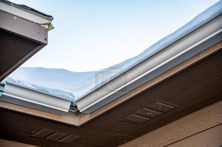 Foto de Metal gutters be installed on a residential buildings with two sections coming together for a 90 degree connection. . High quality photo - Imagen libre de derechos