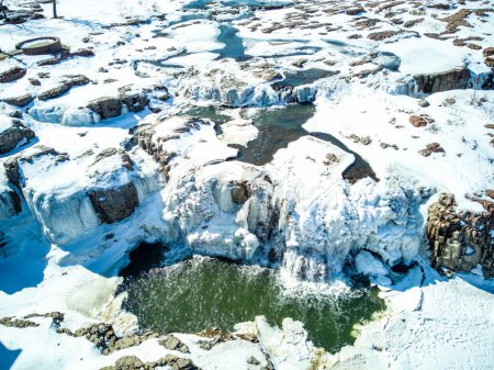 Téléchargez les photos : Cascade du parc Sioux Falls avec glace et neige. L'eau de fonte des neiges en cascade se déversant sur le dessus dans une piscine d'eau stagnante. Photo de haute qualité - en image libre de droit