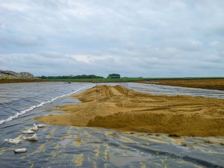 Proyecto de expansión de vertederos con capa de drenaje de arena colocada sobre un revestimiento sintético de HDPE. Foto de alta calidad