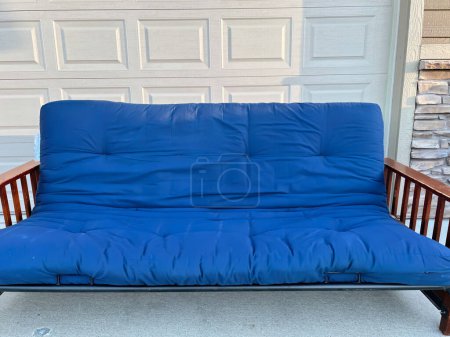 futon and frame on the sidewalk driveway of a house for free pickup . High quality photo