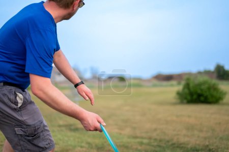 Téléchargez les photos : Concentration sélective sur un adulte caucasien se préparant à lancer un disque golf vers la broche. . Photo de haute qualité - en image libre de droit