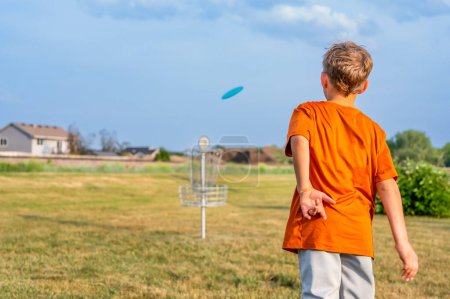 Young Caucasian male boy aiming a disc golf at a chain goal. . High quality photo