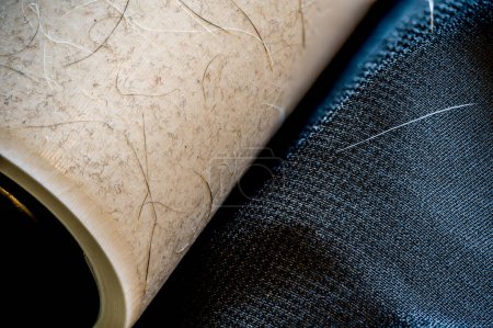 Focus stack of a lint roller resting on a dark suit jacket to remove pet animal hair. High quality photo