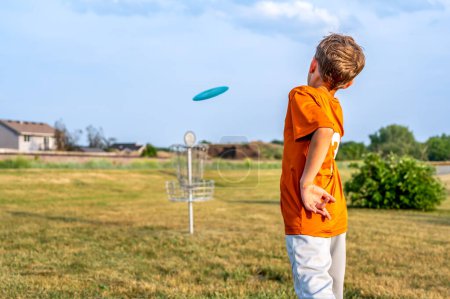 Téléchargez les photos : Jeune garçon caucasien visant un disc golf à un but de chaîne. . Photo de haute qualité - en image libre de droit