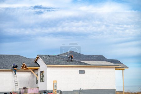 Photo for Shingle roof being installed on a two-story walkout new build residential construction house. . High quality photo - Royalty Free Image