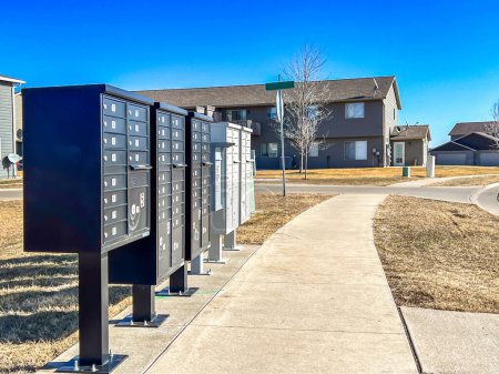 A row of mailboxes stretches along the side of a sidewalk, awaiting the exchange of messages and memories.