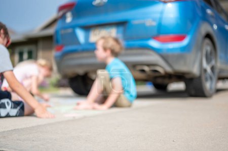 Kinder, die auf einer Auffahrt hinter einem Fahrzeug im toten Winkel sitzen, außer Sicht des Fahrers. . Hochwertiges Foto