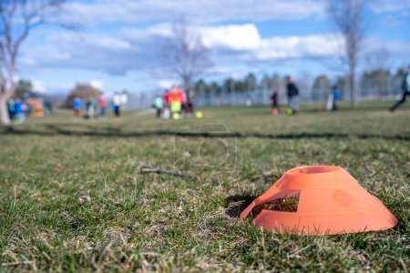 Photo for Selective focus on a soccer practice field cone on grass with blurred kids in the background. High quality photo - Royalty Free Image