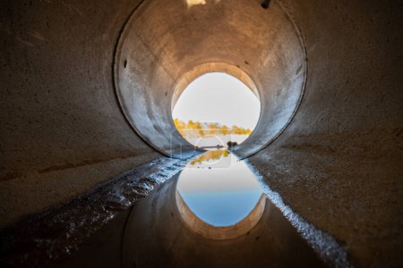 A l'intérieur d'un ponceau circulaire de drainage en béton avec un filet d'eau. Photo de haute qualité