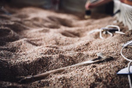 Kind bürstet Sand bei einer Dinosaurier-Fossilien-Ausgrabung weg. . Hochwertiges Foto