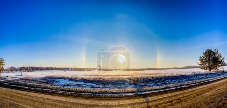 Phénomène optique atmosphérique chiens soleil le matin à travers un champ de neige. . Photo de haute qualité
