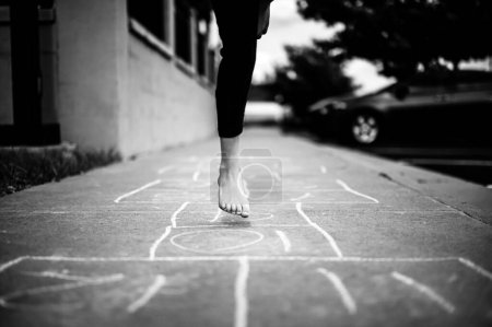 Selective focus on chalk numbers with a girl playing hop-scotch barefoot. High quality photo