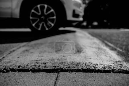 Selective focus on area in front of a speed bump with a car driving over. High quality photo